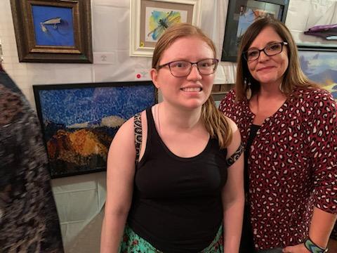 A redheaded lady in front of her painting